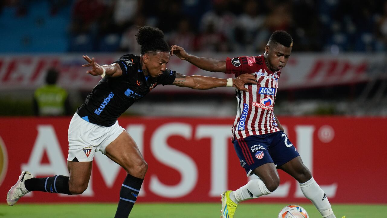 Deiber Caicedo del Junior de Colombia, derecha, y Ricardo Ade de la Liga Deportiva Universitaria de Ecuador, luchan por el balón durante un partido de fútbol del Grupo D de la Copa Libertadores en el Estadio Metropolitano