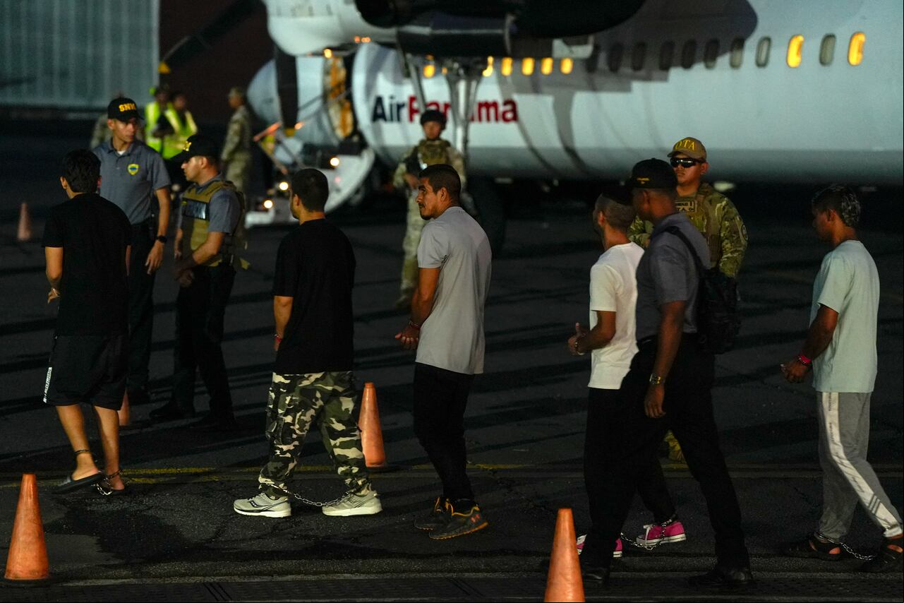 Migrantes colombianos, con las manos y los pies esposados, hacen fila para subir a un avión en el aeropuerto de Albrook Gelabert en la ciudad de Panamá el 20 de agosto de 2024, durante su deportación. Panamá deportó este martes a 29 colombianos con antecedentes penales que habían ingresado al país a través del inhóspito Tapón del Darién, aplicando por primera vez un acuerdo sobre repatriaciones de migrantes firmado con Estados Unidos en julio. (Foto de ARNULFO FRANCO / AFP)
