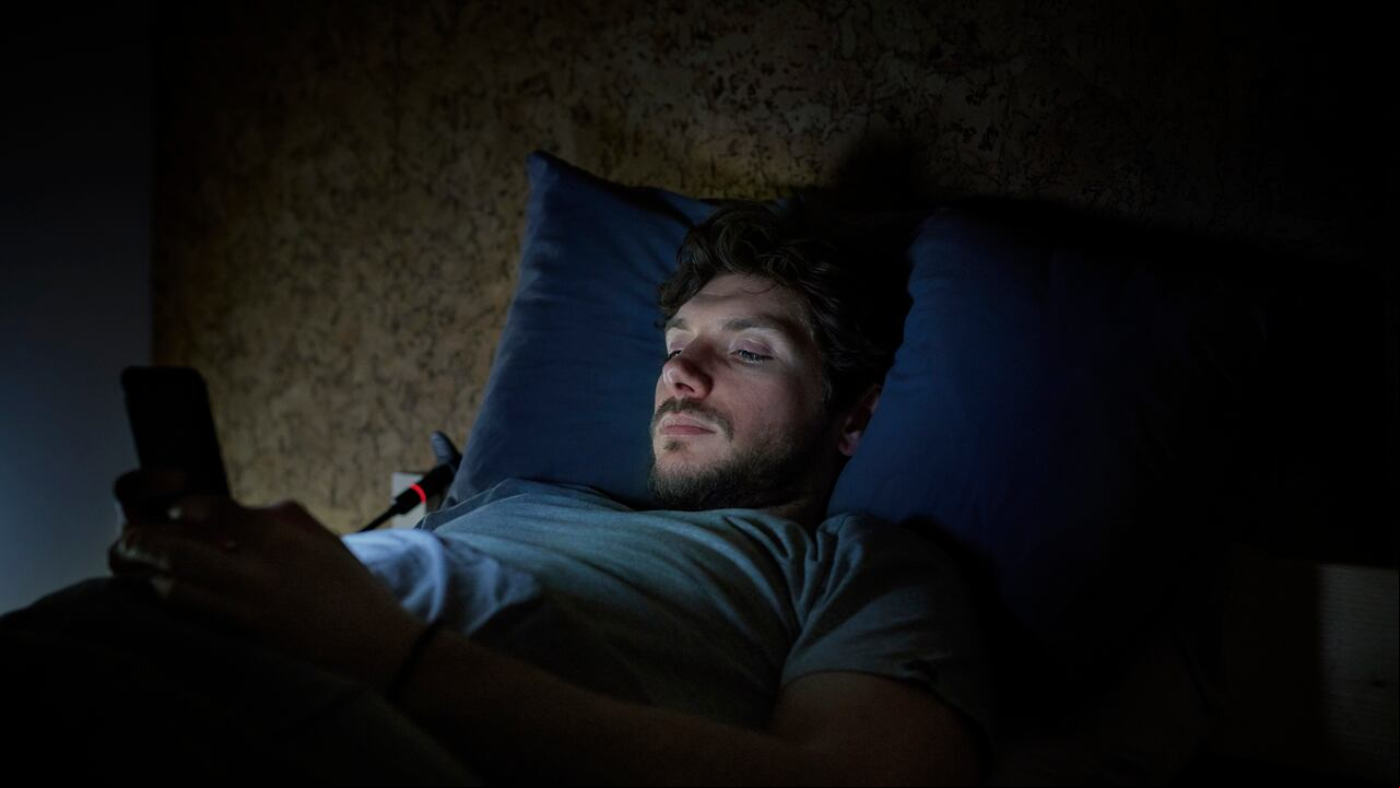 Hombre en la cama manipula su celular