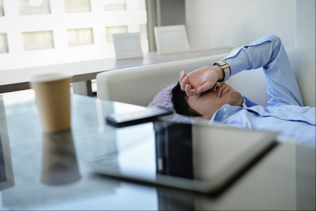 Hombre haciendo su siesta en un sofá, en medio de una jornada laboral