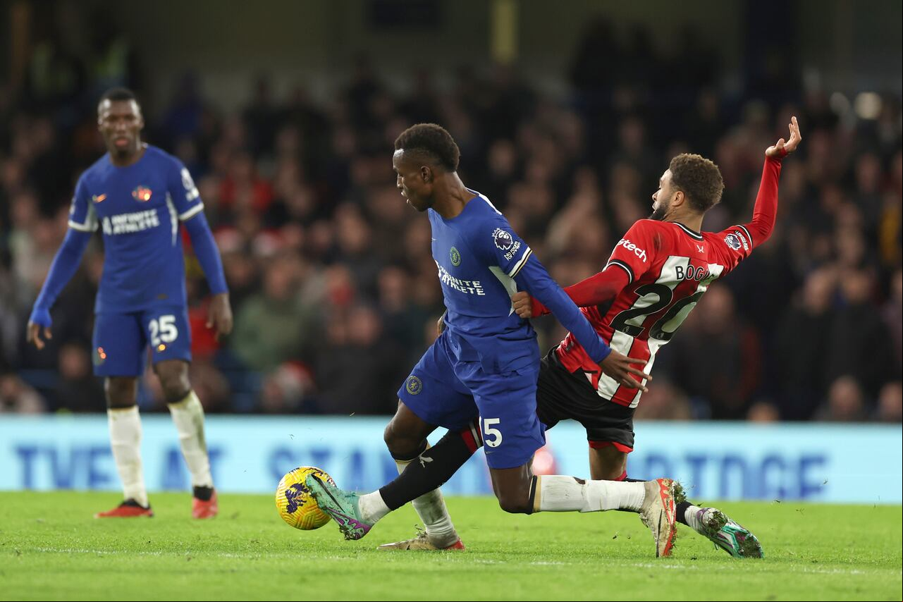 Nicolas Jackson, izquierda, del Chelsea, es abordado por Jayden Bogle del Sheffield United durante el partido de fútbol de la Liga Premier inglesa entre Chelsea y Sheffield United en Stamford Bridge en Londres, el sábado 16 de diciembre de 2023. (Foto AP/Ian Walton)