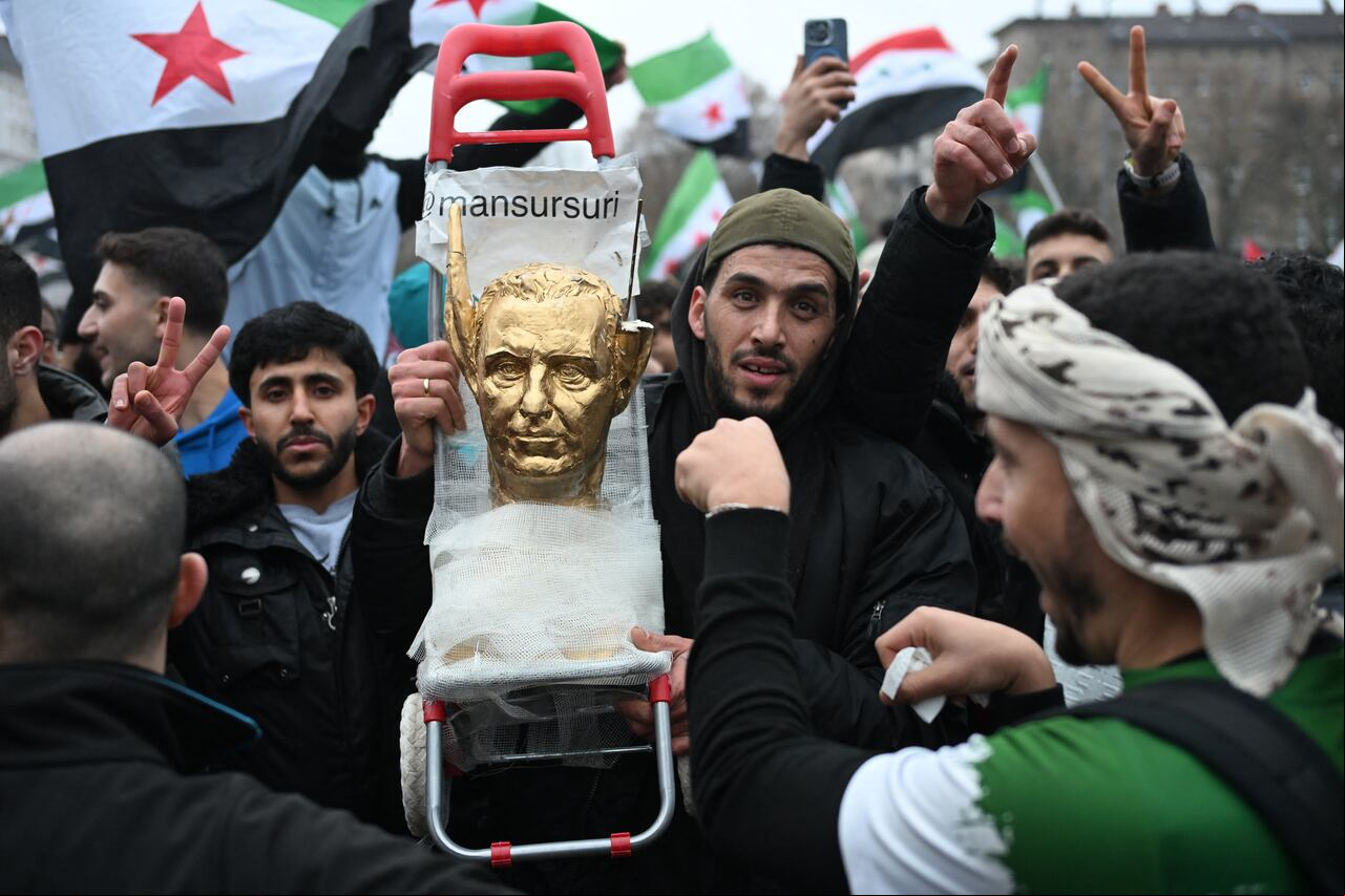 Un manifestante sostiene un busto pintado de oro del dictador sirio Bashar al-Assad con orejas de burro mientras de la comunidad siria se concentran el 8 de diciembre de 2024 en Berlín, Alemania, para celebrar el fin del gobierno del dictador sirio