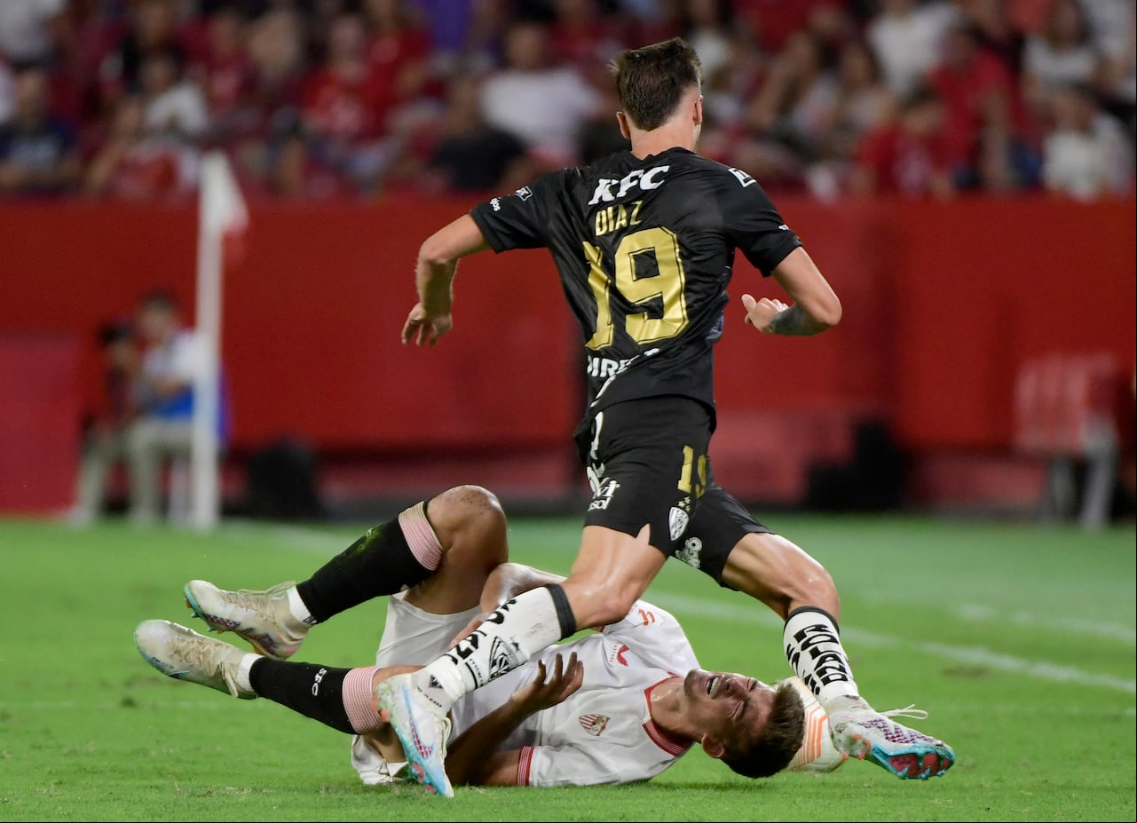 El defensor español del Sevilla, Kike Salas, cae mientras compite con el delantero argentino del Independiente del Valle, Lautaro Díaz.