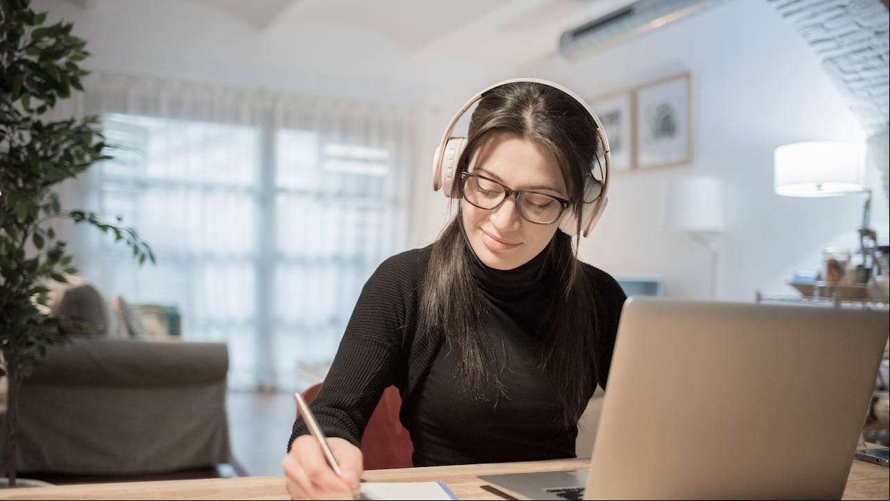 Mujer joven con ordenador portátil en casa. Mujer trabajando desde casa en su computador portatil.