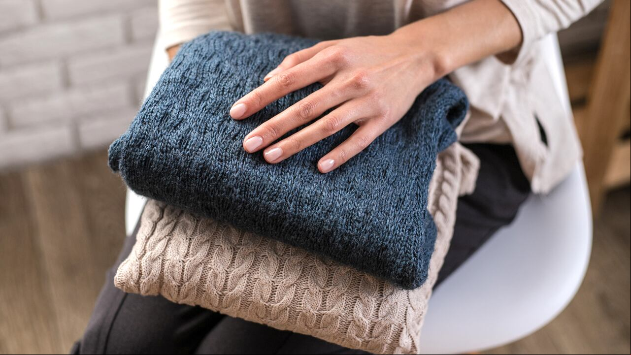 Woman's hands holding knitted clothes. Close up. Concept of cozy home.