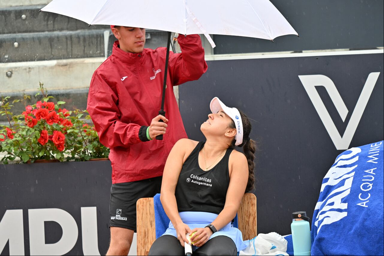 A ball boy protects Colombia's Maria Camila Osorio from the rain with an umbrella during her round of 32 match against 's Caroline Garcia at the Women's WTA Rome Open tennis tournament on May 13, 2023 at Foro Italico in Rome. (Photo by Filippo MONTEFORTE / AFP)