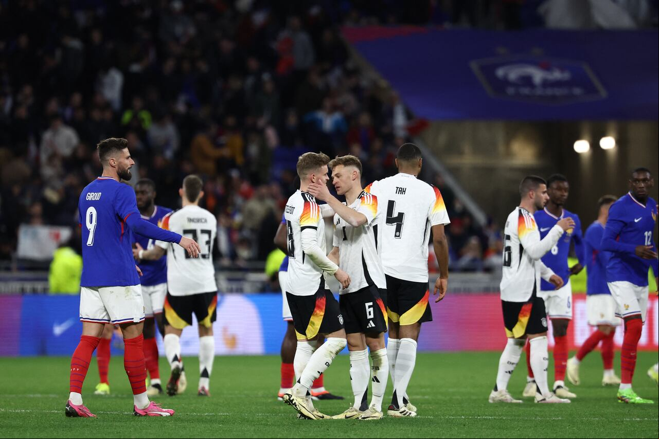 El centrocampista alemán #06 Joshua Kimmich (CR) y el defensor alemán #18 Maximilian Mittelstadt (CL) se abrazan al final del partido amistoso de fútbol entre Francia y Alemania, en el estadio Groupama en Decines-Charpieu, cerca de Lyon, el 23 de marzo de 2024. (Foto de FRANCK FIFE / AFP)