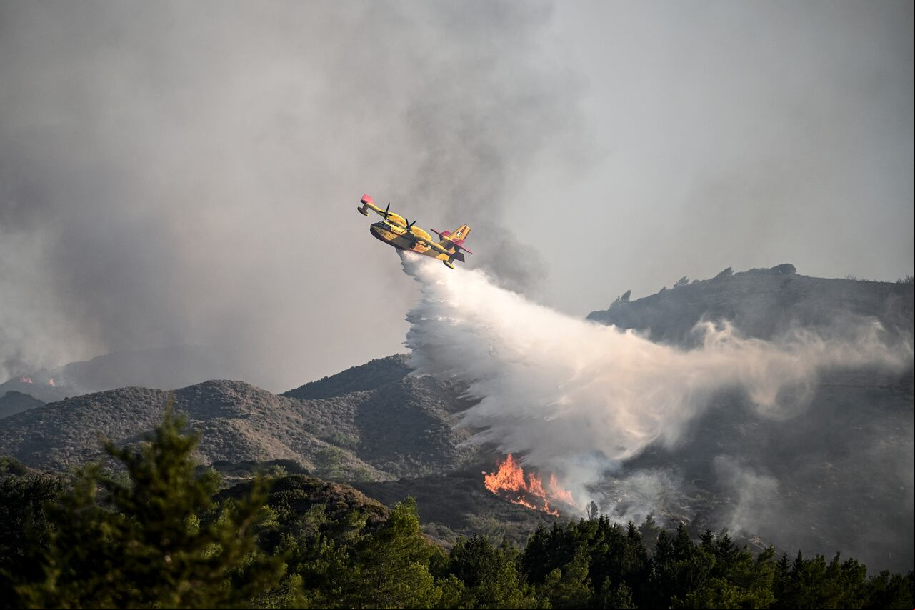 Un avión de extinción de incendios lanza agua sobre un incendio forestal cerca de la aldea de Vati en la parte sur de la isla griega de Rodas, a unos 70 km al suroeste de la ciudad capital el 25 de julio de 2023. (Imagen de referencia)