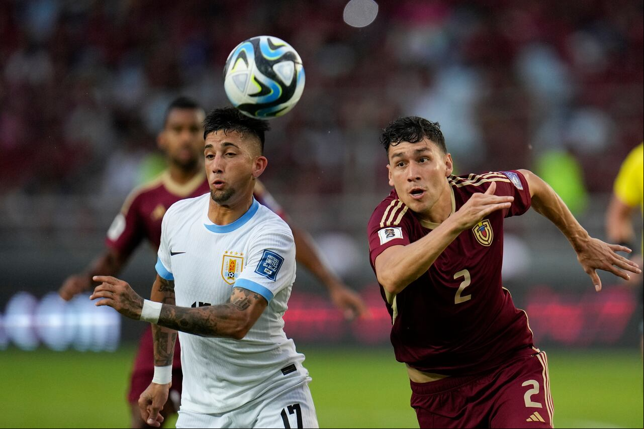 El uruguayo Cristian Olivera (izquierda) lucha por el balón con el venezolano Nahuel Ferraresi durante un partido de clasificación para la Copa Mundial de la FIFA 2026 en el Estadio Monumental de Maturín en Maturín, Venezuela, el martes 10 de septiembre de 2024. (Foto AP/Ariana Cubillos)