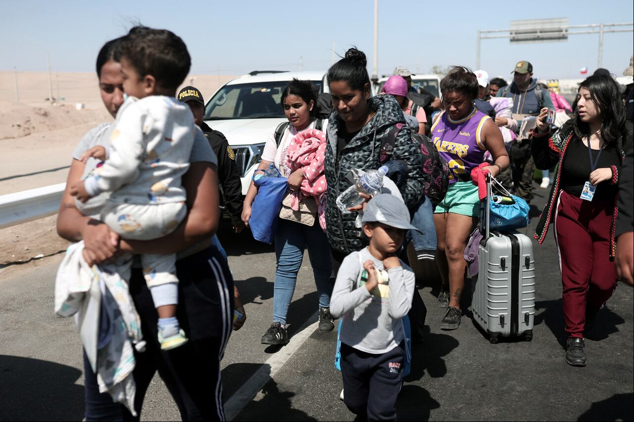 Migrantes de diferentes nacionalidades son escoltados por policías peruanos a una oficina de migración en Tacna, en la frontera entre Perú y Chile, el 28 de abril de 2023. - Chile confirmó que el 7 de mayo partirá un primer vuelo de repatriación para cientos de migrantes venezolanos varados en el fronteriza con Perú que buscan regresar a su país de origen desde hace semanas, dijo el 4 de mayo el canciller chileno, Alberto van Klaveren.