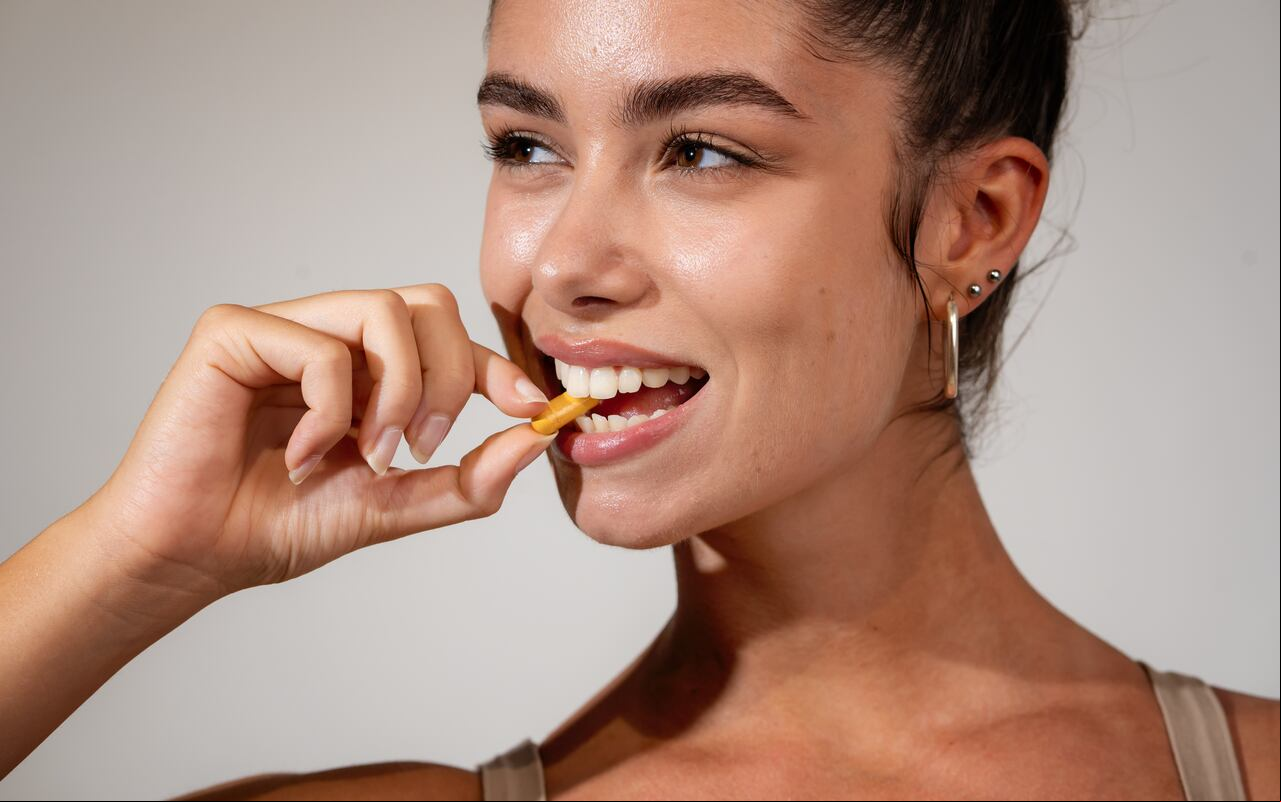Caucasian ethnicity Attractive young adult woman taking vitamin. Studio shot, 20-25 years.