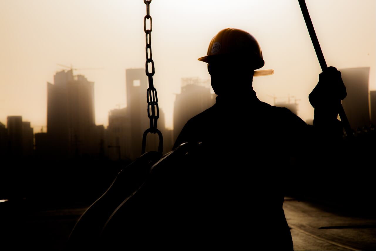 Doha, Qatar - 11 de diciembre de 2017. Trabajadores de la construcción preparando una grúa para trabajar en los rascacielos de fondo en Doha