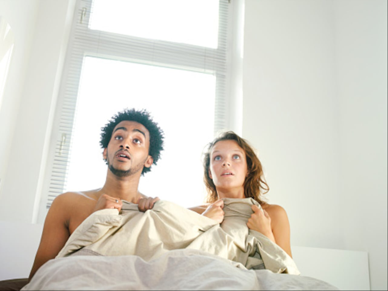 Foto ilustrativa de hombre y mujer en una cama, al parece teniendo relaciones cuando es visto por su esposa.