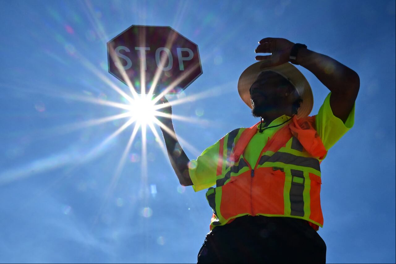 Un controlador de tráfico atiende la esquina de su calle durante un turno de 8 horas bajo el sol en Las Vegas, Nevada, el 12 de julio de 2023, donde las temperaturas alcanzaron los 106 grados en medio de una ola de calor en curso.