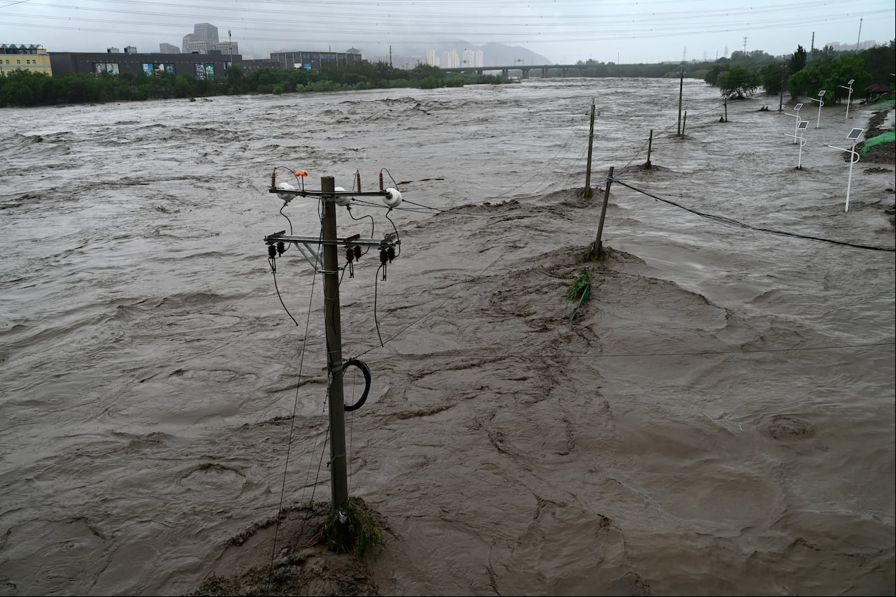 This picture shows a view of the overflooded Yongding river, after heavy rains in Mentougou district in Beijing on July 31, 2023. Heavy rains battered northern China on July 31, killing at least two people in Beijing while washing away cars and inundating subway stations, with the capital issuing its highest alerts for flooding and landslides. (Photo by Pedro PARDO / AFP)