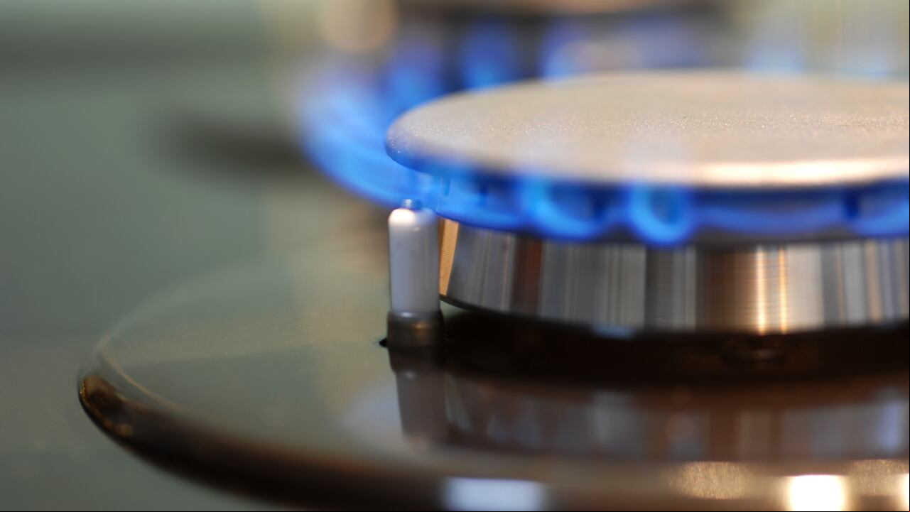 Imagen macro de encimera de gas en plena llama. Concéntrese en el frente del quemador y el encendedor a la izquierda de la llama.