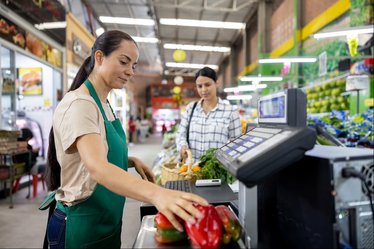 Latin American female cashier ing products while working at the supermarket