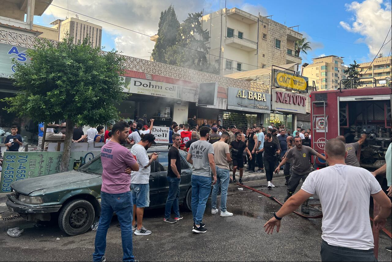 People gather as firefighters put out flames at the site of a device explosion in Saida, southern Lebanon, September 18, 2024. A second wave of device explosions killed three people in the strongholds of Hezbollah in Lebanon on September 18, raising fears of an all-out war between Israel and Iranian-backed militants. (Photo by Mahmoud ZAYYAT / AFP)
