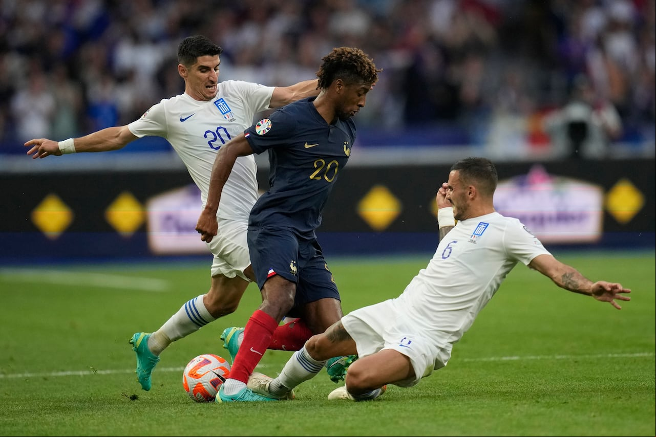 Kingsley Coman, centro, desafía el balón con Petros Mantalos de Grecia, izquierda, y Dimitris Kourbelis durante el partido de fútbol de clasificación del grupo B para la Eurocopa 2024 entre Francia y Grecia en el Stade de , en las afueras de París, el lunes 19 de junio de 2023. (AP Foto/Christophe Ena)